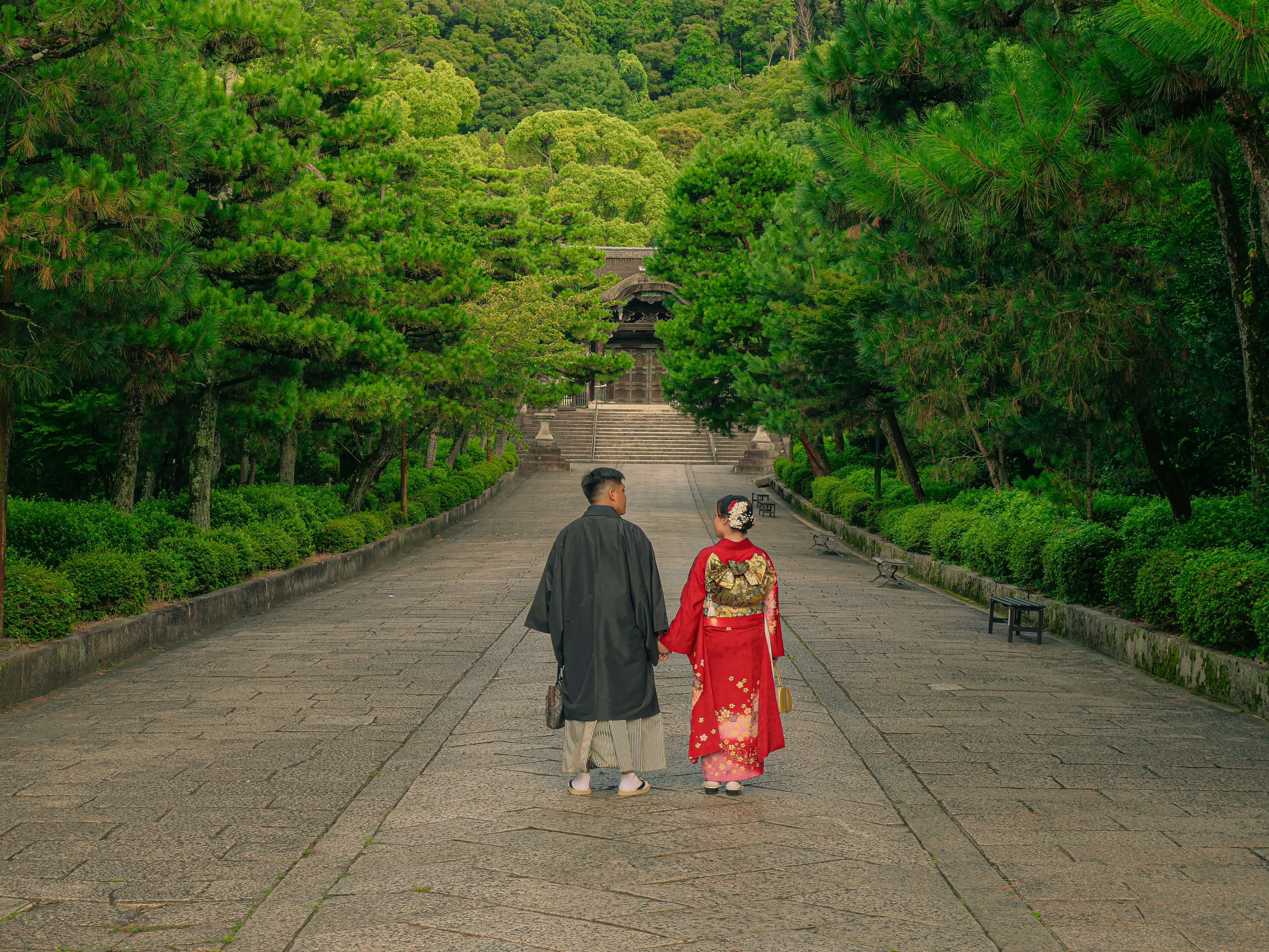 Couple walking in traditional Japanese attire on a tree-lined path